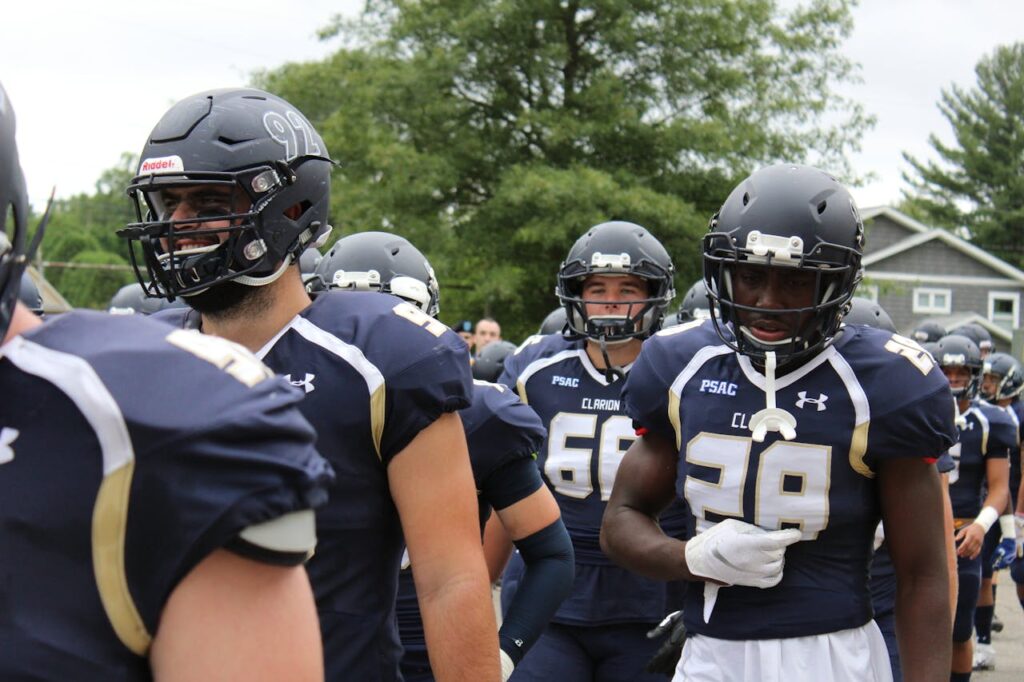 Football players in navy blue uniforms prepare for a game outdoors with determination and team spirit.